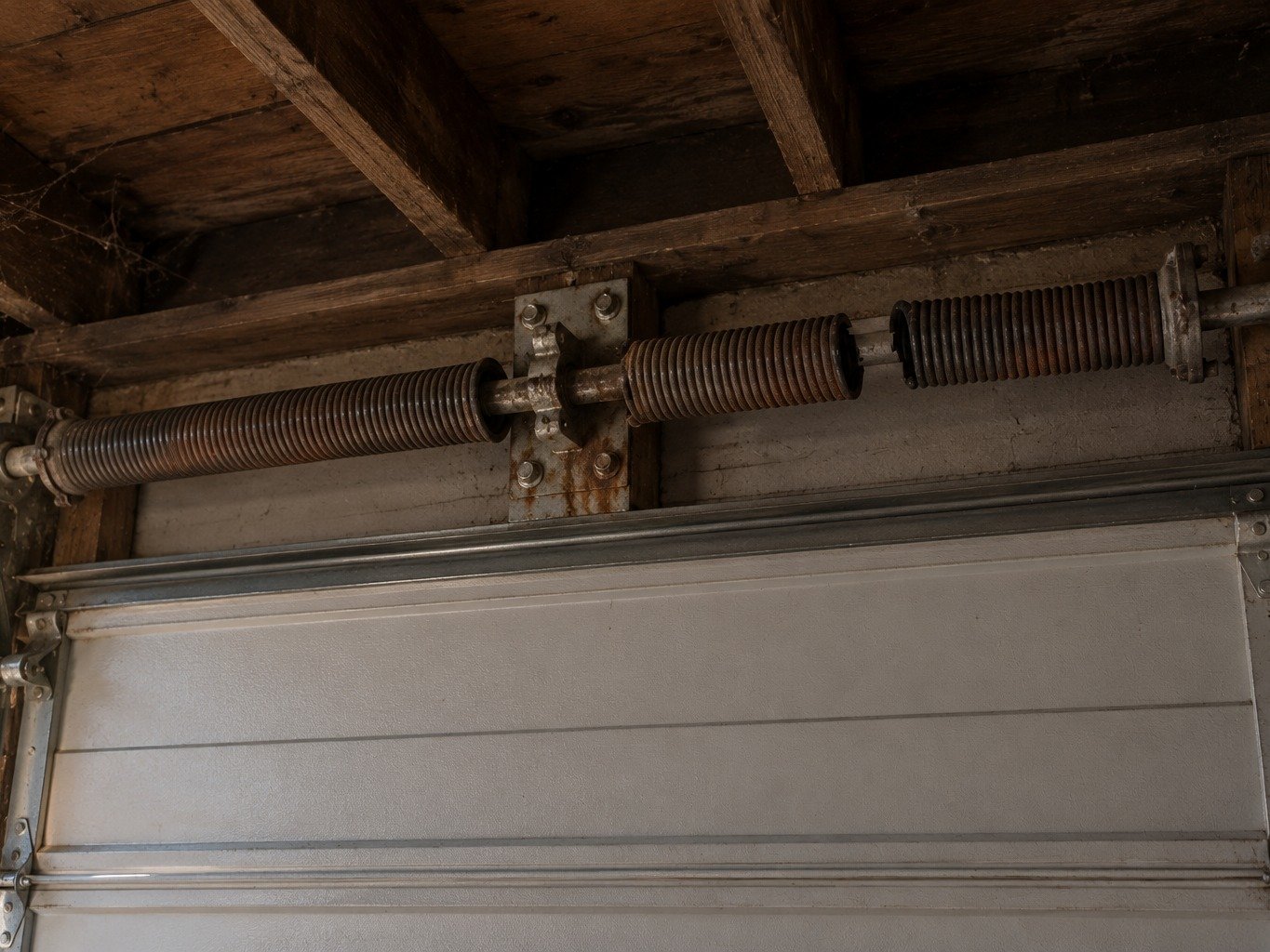 Technician replacing a torsion spring above a garage door